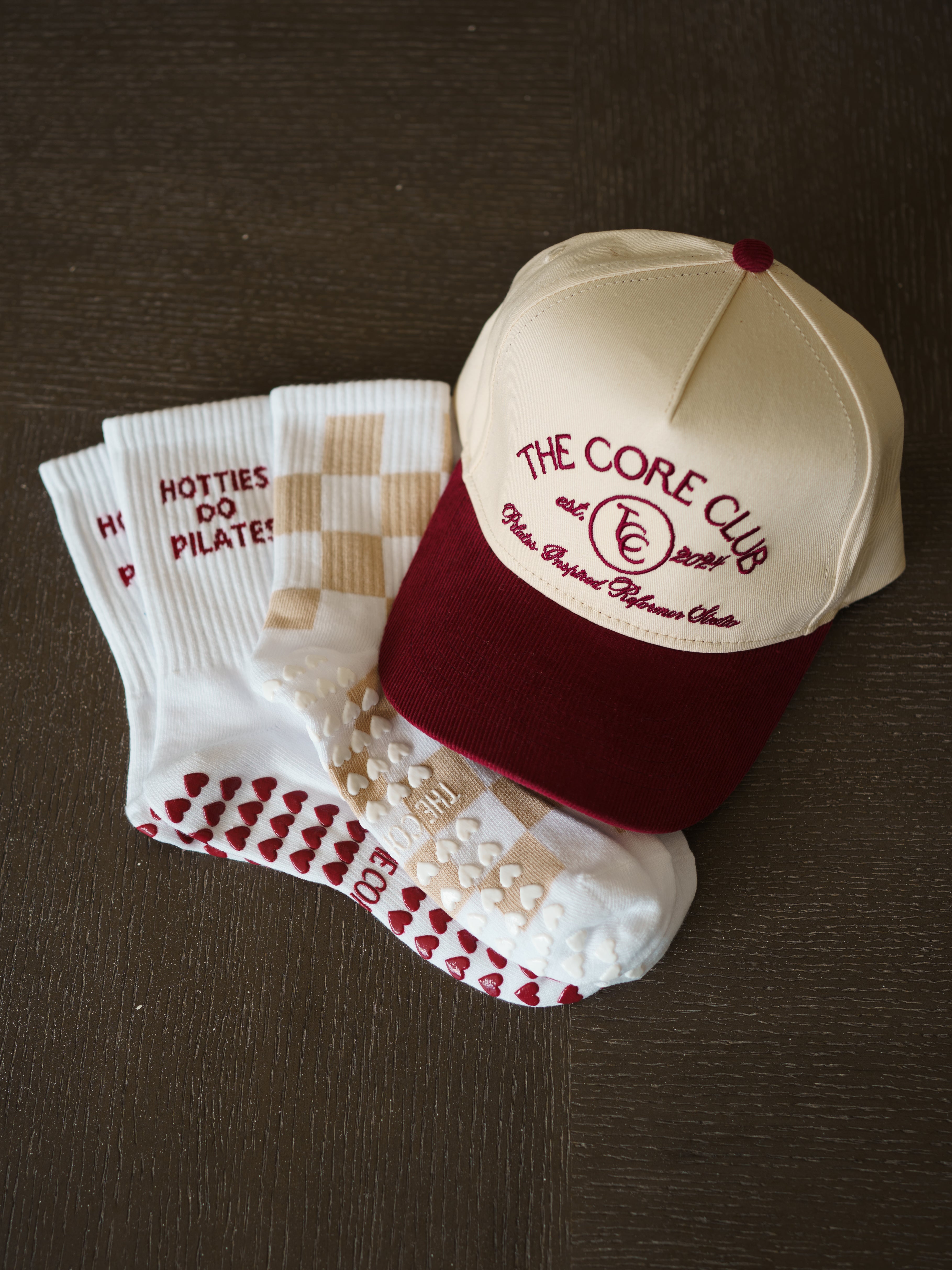 Burgundy TCC Hat with corduroy brim, with hotties do pilates matching socks and white and sand tan checkered grippy pilates socks